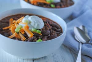 chili in bowls with sour cream and cheese and green onion