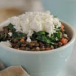 A bowl of lentils topped with goat cheese and spinach