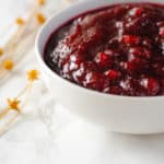 Bowl of spiced cranberry sauce with dried flowers in background