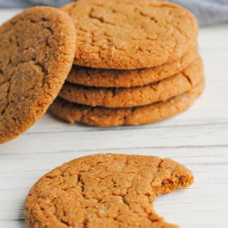 stack of ginger cookies with one to the side and one in front with a bite taken