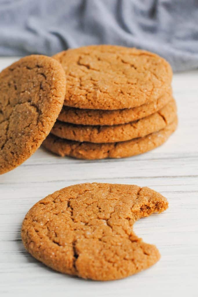 stack of ginger cookies with one to the side and one in front with a bite taken 