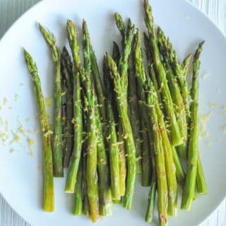 roasted asparagus on white plate with lemon zest