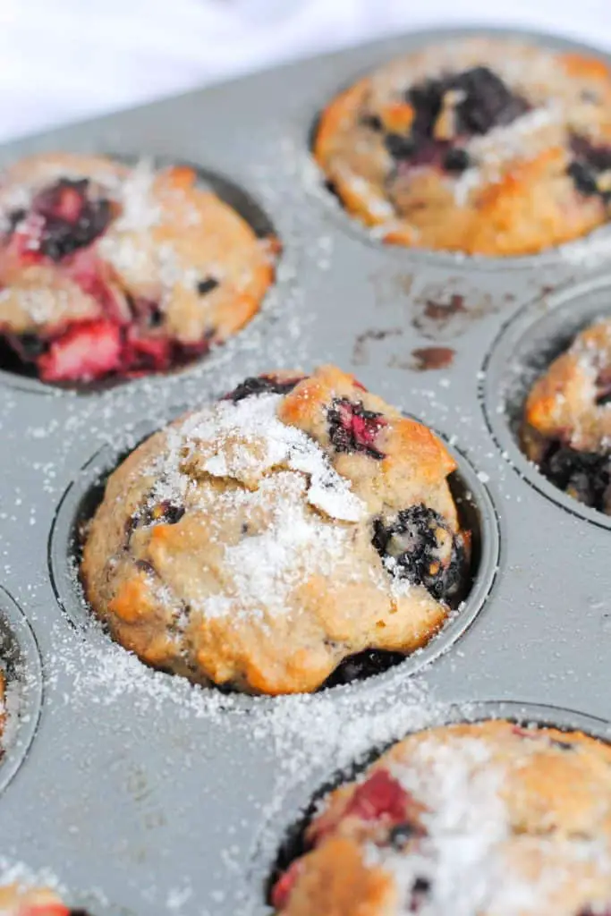 mixed berry muffins in muffin tin and topped with white sugar