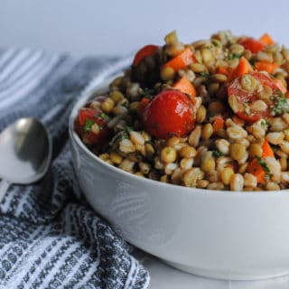 lentil salad in white bowl next to gray cloth