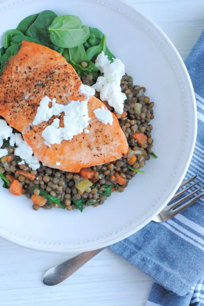 plate of lentils and spinach with salmon topped with goat cheese