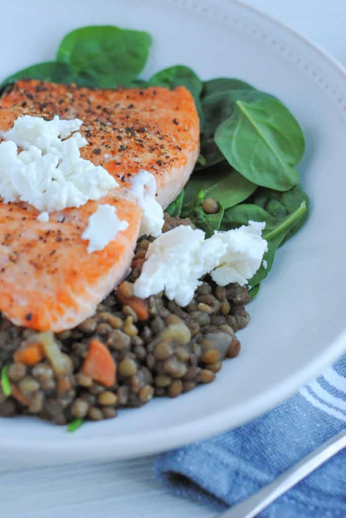 plate of lentils and spinach with salmon topped with goat cheese