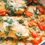 skillet with salmon in a creamy garlic, spinach and tomato sauce