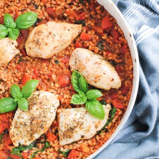 skillet with cooked farro, tomatoes, chicken and basil