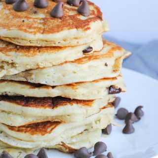 stack of buttermilk pancakes topped with chocolate chips on white plate