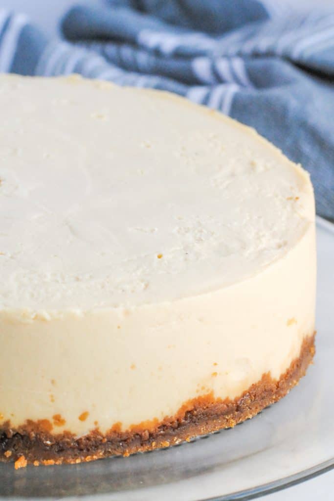 cheesecake on a white plate with gray and white striped towel in background