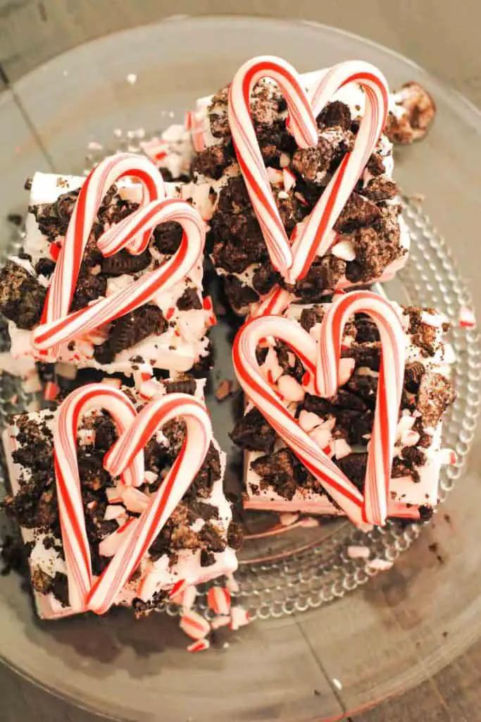 squares of peppermint surprise ice cream dessert topped with crushed oreos and candy cane in heart shape