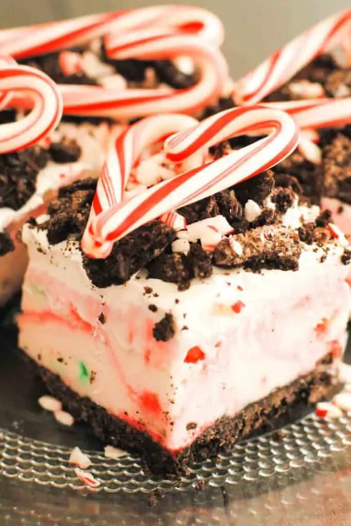 a square of peppermint surprise ice cream dessert topped with crushed Oreos and candy cane in heart shape