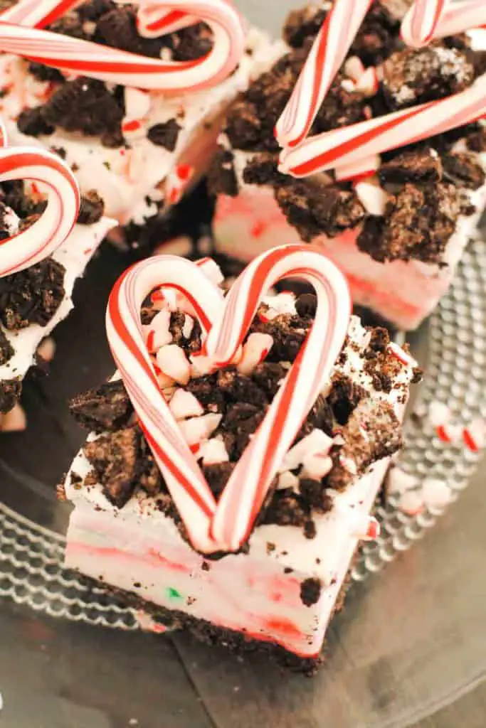 squares of peppermint surprise ice cream dessert topped with crushed oreos and candy cane in heart shape